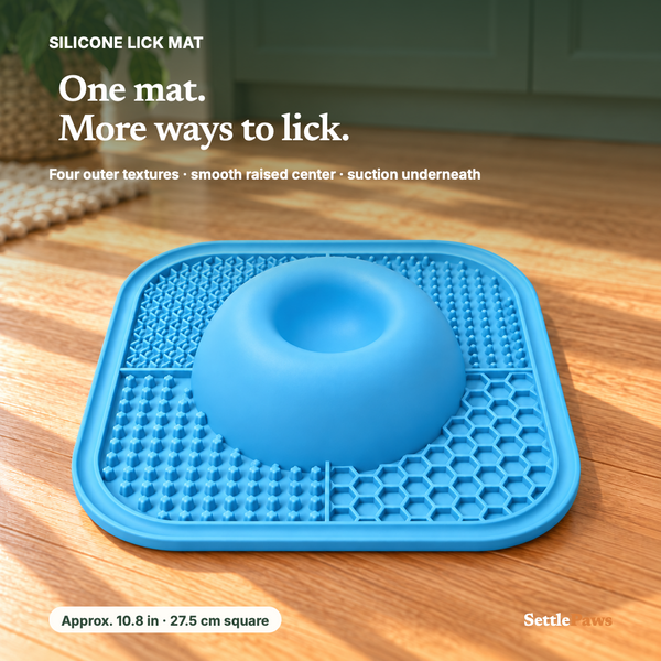 SettlePaws blue silicone dog lick mat with four textured corners and smooth raised center on a wood floor